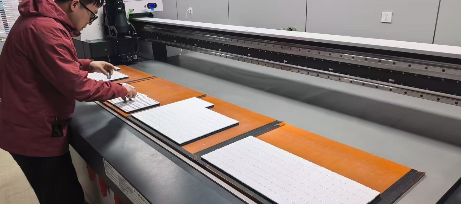 Worker arranging Mahjong tile blanks on production equipment