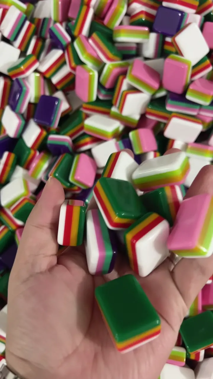 Colorful layered acrylic Mahjong tile blanks held above a production batch